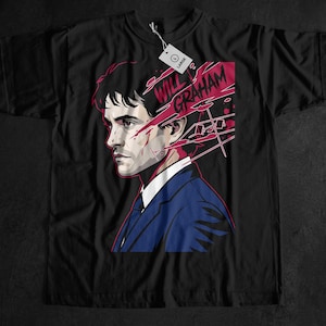 Könnte beinhalten: Schwarzes T-Shirt mit einem stilisierten Porträt eines Mannes in einem blauen Anzug mit dem Namen "WILL GRAHAM" in Rot. Das Design hat einen Comic-Stil mit roten und weißen Akzenten. Ein weißes Etikett ist angebracht.