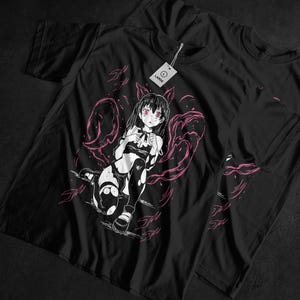 May include: Black t-shirt with a manga-style illustration of a female character with pink details. The character has black hair, pink eyes, and wears a black and white outfit. A tag on the shirt reads "Large".