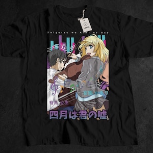 May include: Black t-shirt featuring an anime-style illustration of two characters playing musical instruments. The design includes text in Japanese and English, with musical notes and colorful accents. A tag is attached to the shirt.