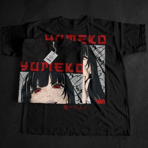 May include: Black t-shirts featuring a graphic of an anime character with red eyes and black hair. The word "Yumeko" is printed in red block letters above the image. The t-shirts are folded and stacked.