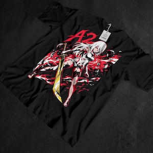 May include: Black graphic t-shirt featuring a white-haired anime character with a golden sword, set against a red and white background. The word "A2" is in red at the top. A white tag reads "LARGE".
