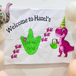 May include: A white banner with the text "Welcome to Hazel's" and a green dinosaur footprint that says "TEA-Rex Party!". A pink dinosaur with a party hat and a green teapot is on the right. Balloons surround the banner.