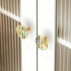 May include: A set of three ceramic mugs with a speckled, matte finish. The mugs are in shades of cream, light gray, and dark gray. Each mug has a simple, minimalist design and a rounded handle.