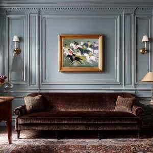 May include: A room with blue paneled walls, a brown velvet sofa, and a framed painting of horses. Two lamps with beige shades and a dark wood table are also visible. The room has a classic, elegant style.