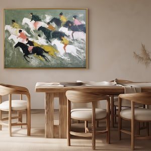 May include: An abstract painting of a horse race hangs above a wooden dining table. The artwork features riders on horses in motion, with a palette of green, black, yellow, and pink. The room includes wooden chairs and a vase of dried plants.