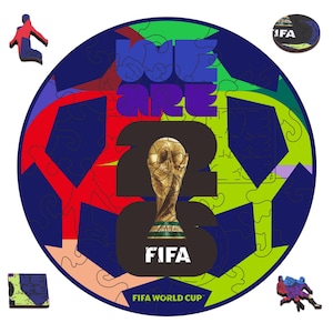 Puede incluir: Un rompecabezas de madera colorido con forma de balón de fútbol, con el texto "WE ARE 22" y el trofeo de la Copa Mundial de la FIFA. Incluye varias piezas de rompecabezas y el logo de la FIFA.
