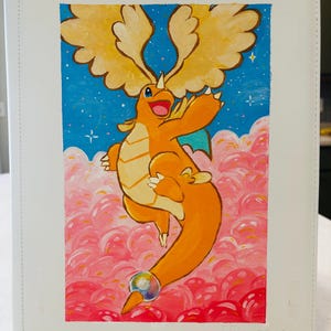 May include: White binder with a colorful painting of a cartoon dragon. The dragon is orange with yellow wings and is set against a blue sky with pink clouds. The binder has the words "Ultra PRO" printed on the bottom right.