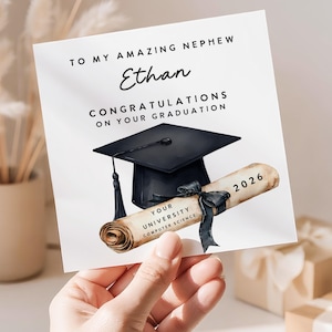 May include: A graduation card with the text "TO MY AMAZING NEPHEW Ethan CONGRATULATIONS ON YOUR GRADUATION". The card features a black graduation cap and a scroll with the year 2026. The scroll reads "YOUR UNIVERSITY COMPUTER SCIENCE".