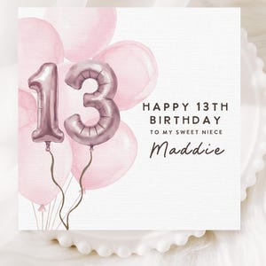 May include: A birthday card with a watercolor design. The card features pink balloons and a metallic number 13 balloon. Text reads "Happy 13th Birthday to my sweet niece Maddie."