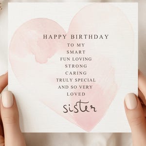 May include: A birthday card with a pink watercolor heart design. The card reads "Happy Birthday to my smart, fun loving, strong, caring, truly special, and so very loved sister."