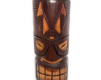 May include: A brown wooden tiki statue with a carved face and a crown on top. The statue has a detailed design with orange and brown accents.