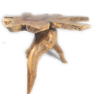 May include: A side table crafted from a single piece of light brown wood, featuring a natural, irregular live-edge circular top and a sturdy, organic root-like base that extends into three distinct, tapered legs supporting the structure.