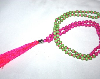 May include: A pink and green beaded necklace with a silver charm and a pink tassel.