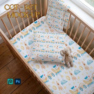 May include: A cot set mock-up featuring a crib with bedding. The bedding has a white background with a pattern of yellow cars, rockets, clouds, and stars. A small stuffed elephant toy rests on the pillow. The text "COT - SET MOCK-UP" is at the top.