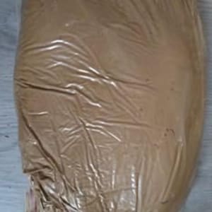 Puede incluir: Una bolsa de plástico grande, marrón y opaca, llena de una sustancia sólida, probablemente granular. La bolsa está sellada y tiene una textura arrugada, lo que sugiere que es flexible. El contenido no es visible.