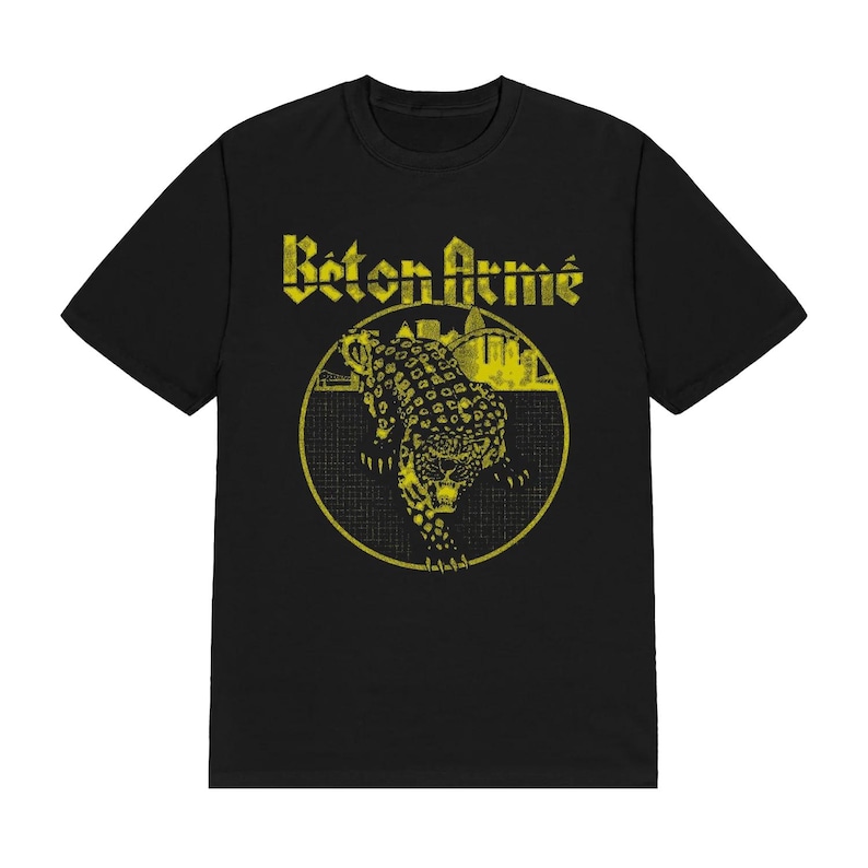 K&ouml;nnte beinhalten: Ein schwarzes Kurzarm-T-Shirt mit einem gelben Grafikdruck auf der Brust. Das Design zeigt den Schriftzug "B&eacute;ton Arm&eacute;" &uuml;ber einem kreisf&ouml;rmigen Emblem, das einen stilisierten Leoparden und eine Stadtsilhouette vor einem Rasterhintergrund enth&auml;lt.