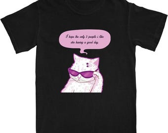 Könnte beinhalten: Schwarzes T-Shirt mit einer Cartoon-Illustration einer weißen Katze mit lila Sonnenbrille. Die Katze hebt ihre Pfote und hat eine rosa Sprechblase darüber mit dem Text: "Ich hoffe, die einzigen 3 Leute, die ich mag, haben einen guten Tag."