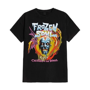 May include: Black t-shirt featuring a colorful graphic design. The design includes the text "FROZEN SOUL" in a stylized font above a skull with glowing blue eyes. Below the skull, the text reads "CREATURE OF THE WHEEL". The artwork has a vintage, distressed look.