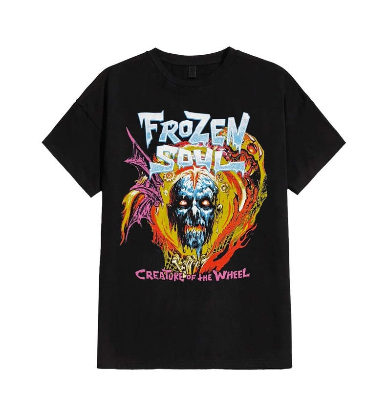 May include: Black t-shirt featuring a colorful graphic design. The design includes the text "FROZEN SOUL" in a stylized font above a skull with glowing blue eyes. Below the skull, the text reads "CREATURE OF THE WHEEL". The artwork has a vintage, distressed look.
