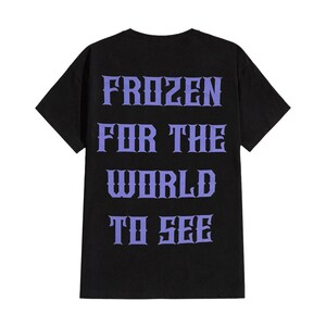 May include: Black t-shirt with the text "FROZEN FOR THE WORLD TO SEE" in a stylized purple font. The shirt has a crew neck and short sleeves. The text is centered on the back of the shirt.