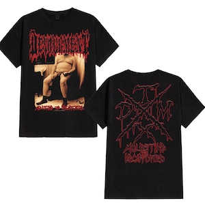 Puede incluir: Camisetas negras con gráficos de la banda Devourment. La parte delantera muestra una persona sentada con el nombre de la banda en rojo. La parte trasera de la camiseta tiene el logotipo de la banda y las palabras "Molesting the Decapitated" en rojo.