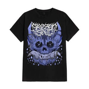 May include: Black t-shirt featuring a detailed, blue and white graphic of a skull with intricate, stylized details. The design includes text at the top and is set against a plain black background. The shirt is a standard crew neck.