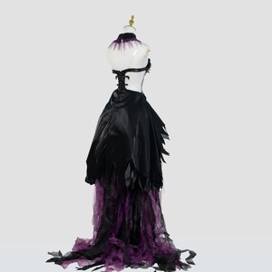 May include: A black and purple costume dress on a mannequin. The dress features a black bodice with a halter neck and a flowing skirt with tattered edges. The skirt transitions to a purple tulle hem. The mannequin has a gold-colored head.