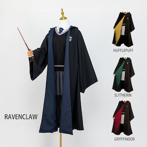 May include: A black and navy blue Ravenclaw robe with a matching wand, displayed on a mannequin. The image also shows three other robes: Hufflepuff (yellow), Slytherin (green), and Gryffindor (red).