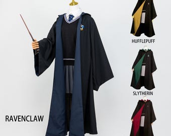 May include: A black and navy blue Ravenclaw robe with a matching wand, displayed on a mannequin. The image also shows three other robes: Hufflepuff (yellow), Slytherin (green), and Gryffindor (red).