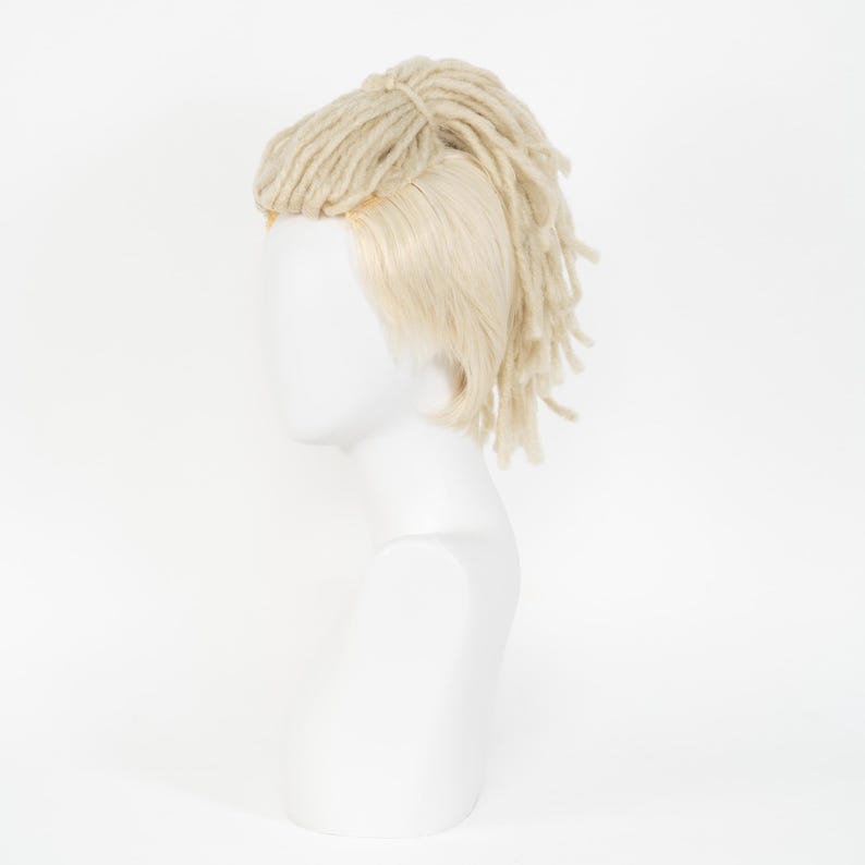 May include: A blonde wig with dreadlocks and a side part, displayed on a white mannequin head. The dreadlocks are a light beige color and are tied up at the crown of the head. The wig has a natural-looking hairline.