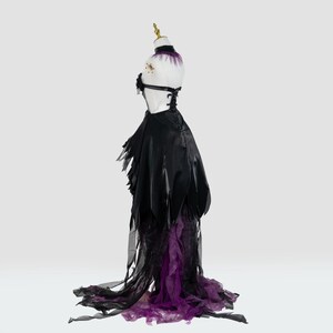 May include: A black and purple costume dress displayed on a mannequin. The dress features a black bodice with a lace-up back and a flowing skirt with tattered edges. The skirt transitions to a purple, layered, sheer fabric at the hem.