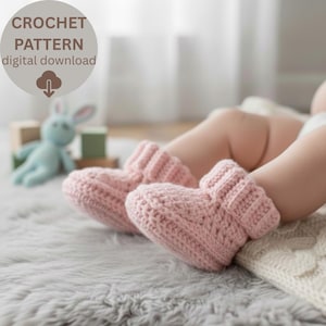 May include: A pair of soft pink crochet baby booties. The booties are on a baby's feet, resting on a gray, fluffy rug. The image includes the text "CROCHET PATTERN digital download". A blue stuffed bunny and wooden blocks are in the background.
