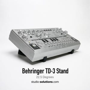 Puede incluir: Un sintetizador Behringer TD-3 plateado sobre un soporte negro, inclinado a 22,5 grados. El sintetizador tiene numerosas perillas y botones. El texto "Behringer TD-3 Stand" se muestra debajo.