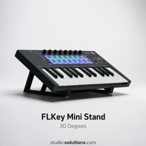 May include: Black FLKey Mini Stand with a 30-degree angle, featuring a keyboard with white and black keys, and a control panel with knobs and illuminated pads. The stand is designed for studio use.