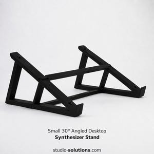 May include: A black metal desktop stand for synthesizers featuring a 30-degree angled design with two side frames connected by horizontal support bars. The text below reads: Small 30° Angled Desktop Synthesizer Stand studio-solutions.com.