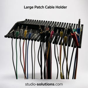 May include: A black plastic Large Patch Cable Holder with multiple slots holding various colored audio cables. The device features a grid-like structure for organizing patch cords. The text "Large Patch Cable Holder" and "studio-solutions.com" are visible.