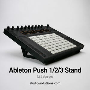 May include: Black Ableton Push 1/2/3 stand angled at 22.5 degrees. The stand has a grid of white square buttons and black knobs. The text "Ableton Push 1/2/3 Stand" and "studio-solutions.com" are visible.