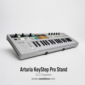 May include: A gray Arturia KeyStep Pro Stand with black and white keys, knobs, and buttons. The stand is angled at 22.5 degrees. The text "Arturia KeyStep Pro Stand" and "studio-solutions.com" are visible.