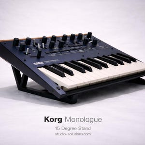 May include: A dark blue Korg Monologue synthesiser on a black 15-degree stand. The synthesiser has black and white keys, black knobs, and a wooden accent. The text "Korg Monologue" and "15 Degree Stand" are visible.