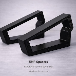 May include: Two black 5HP Eurorack synth spacers. The rectangular spacers have an open center and are angled. The text "5HP Spacers" and "Eurorack Synth Spacer Pair" is visible. The website studio-solutions.com is also visible.