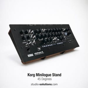 May include: A black Korg Minilogue XD synthesizer on a wooden stand, angled at 45 degrees. The synthesizer features numerous knobs, buttons, and a small display. The text "Korg Minilogue Stand" and "45 Degrees" is visible.