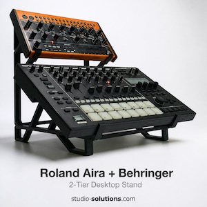 Puede incluir: Un soporte de escritorio negro de 2 niveles que sostiene dos dispositivos de producción de música electrónica. El dispositivo superior es naranja y negro, mientras que el dispositivo inferior es negro con teclas blancas. El soporte es de metal negro. El texto en la imagen dice "Roland Aira + Behringer 2-Tier Desktop Stand studio-solutions.com".