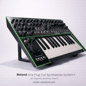Pode incluir: Um sintetizador Roland Aira Plug Out System-1 preto e verde com teclado e vários botões. O sintetizador está em um suporte de mesa de 45 graus. O texto "Roland Aira Plug Out Synthesizer System-1" é visível.