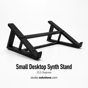 May include: A black wooden desktop synth stand. The stand is angled and has a horizontal support beam. The text "Small Desktop Synth Stand" is below the stand, along with "22.5 Degrees" and "studio-solutions.com".