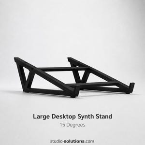 Könnte beinhalten: Ein schwarzer Synth-Ständer mit geometrischem Design. Der Ständer ist mit "Large Desktop Synth Stand" beschriftet und um 15 Grad abgewinkelt. Die Website studio-solutions.com ist ebenfalls sichtbar.