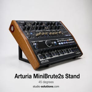 May include: Arturia MiniBrute 2s stand with a 45-degree angle. The stand features a black base and wooden side panels. The synthesizer has numerous knobs, buttons, and keys. The text "Arturia MiniBrute2s Stand" is displayed below the synthesizer.