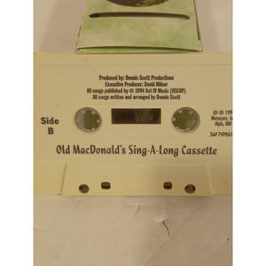 May include: An off-white audio cassette tape labeled Side B with the text Old MacDonald's Sing-A-Long Cassette. The tape includes production credits for Dennis Scott Productions and David Milner, with a 1994 copyright date and catalog number SA# 749961.