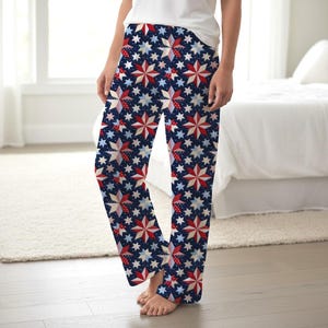 May include: Navy blue pajama pants with a repeating pattern of red, white, and blue stars. The stars are in various sizes and styles, creating a patriotic design. The pants are made of a soft, comfortable material.