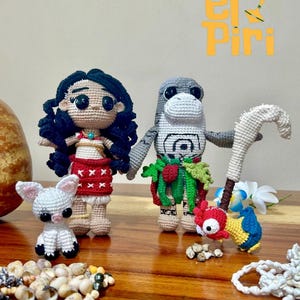 May include: Crocheted dolls of a girl and a shark, with a small white animal, a bird, and a staff. The girl doll has a red skirt and a blue necklace. The shark doll has a green skirt. The bird is yellow, red, and blue.