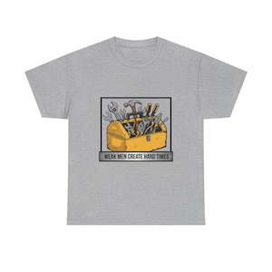 Könnte beinhalten: Hellgraues T-Shirt mit einer gelben Werkzeugkasten-Grafik, gefüllt mit Werkzeugen. Der Werkzeugkasten befindet sich in einem schwarzen Rechteck, darunter der Text "WEAK MEN CREATE HARD TIMES".